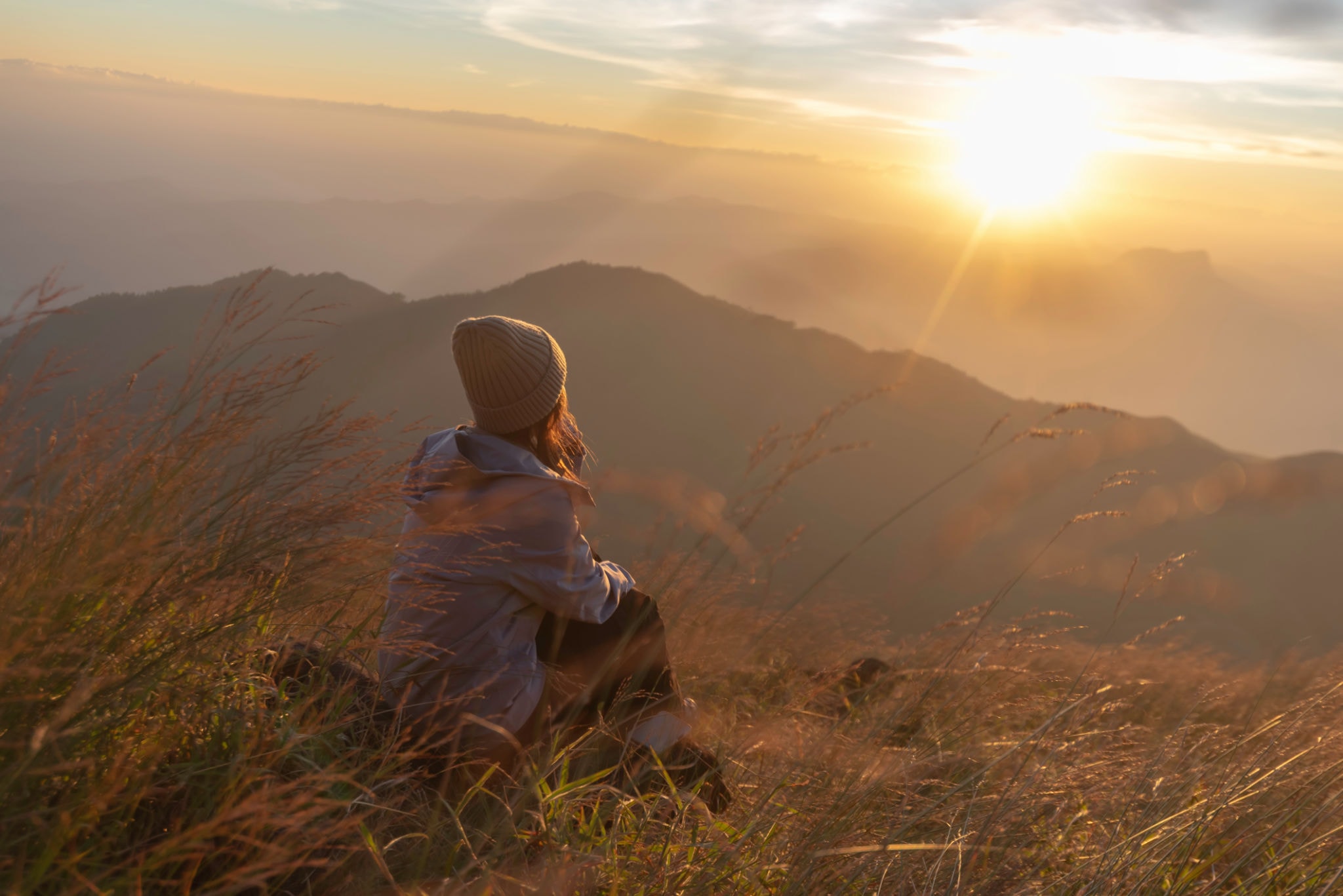Woman sitting on a mountain watching the sunset — gentle release therapy